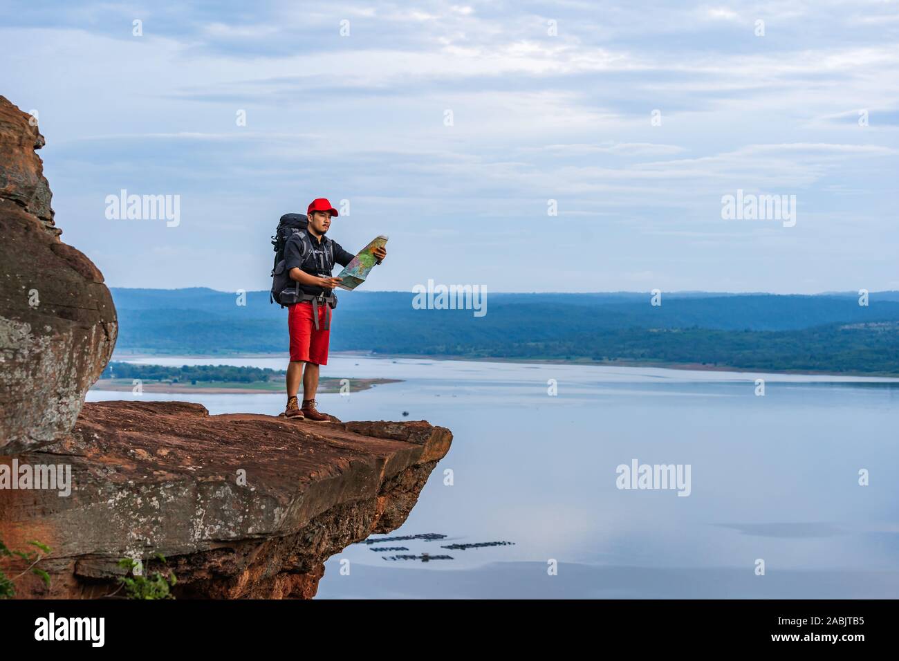 Mann Reisender mit Rucksack auf die Karte am Rand der Klippe, an der Spitze der Rock Mountain Stockfoto