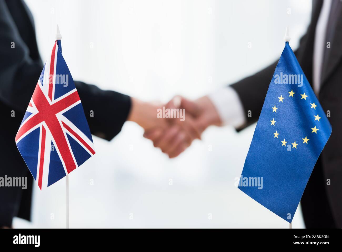 7/8-Ansicht von Botschaftern Händeschütteln in der Nähe von Europäische Union und Großbritannien Flaggen Stockfoto