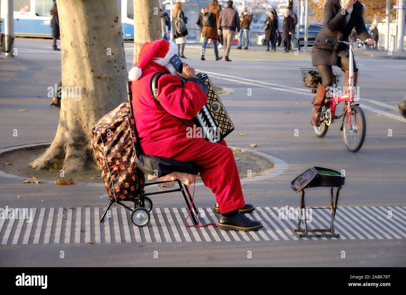 Seitenansicht des Street Performer in Santa Claus Kostüm sitzen, sprechen auf seinem Handy. in Zürich, Schweiz Stockfoto