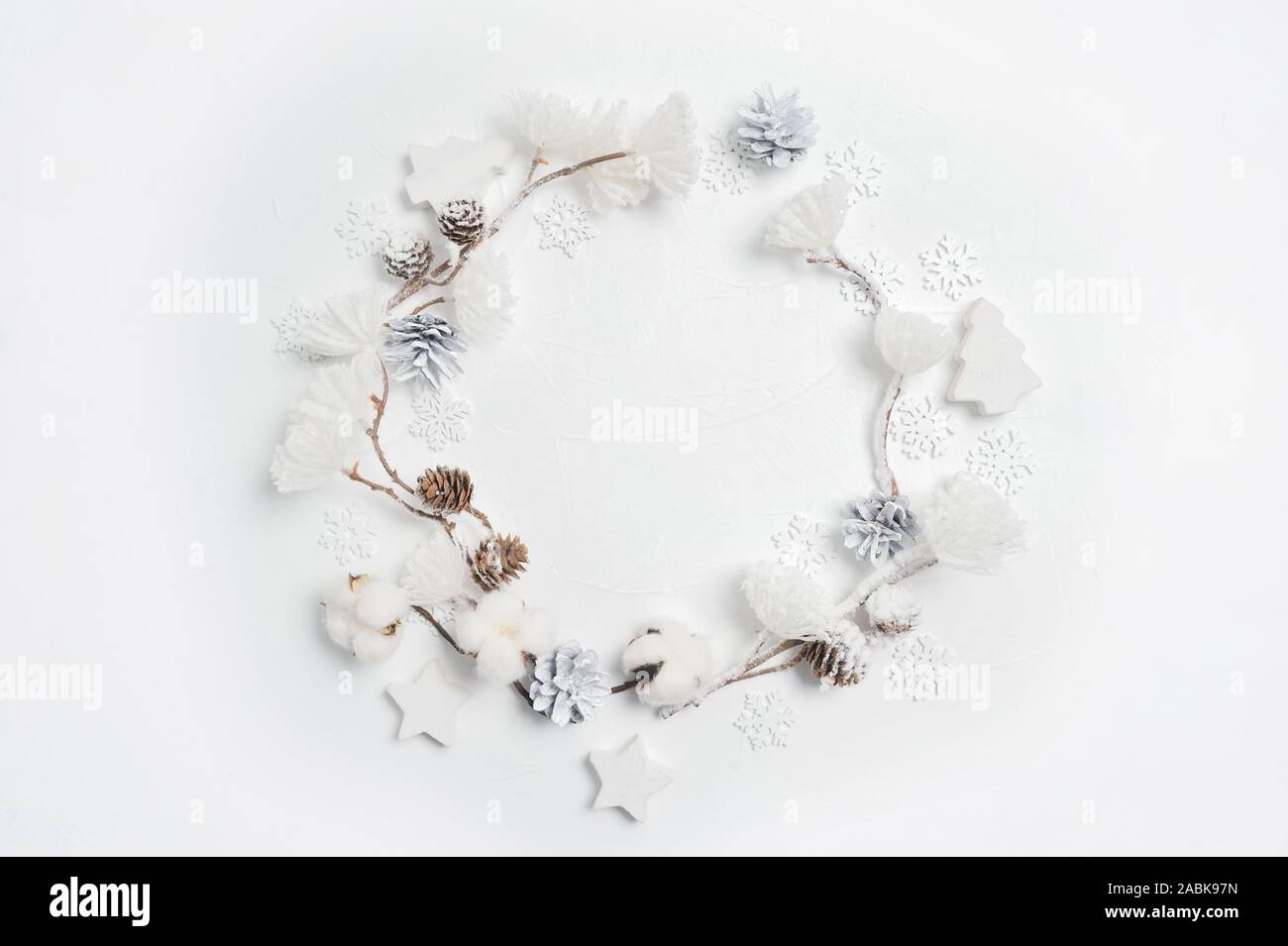 Weihnachten Kranz aus Holz- Schneeflocken, Baumwolle, Blumen, Tannenzapfen und weiße Blume Pompons. Weißer Hintergrund. Flach, Ansicht von oben Stockfoto