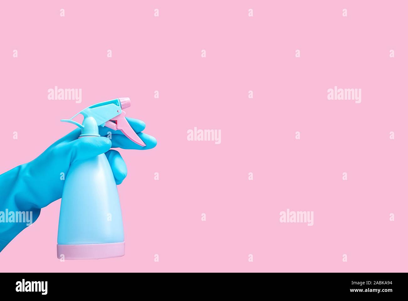 Hand in blau Gummihandschuh holding Reinigung Spray flasche Reinigungsmittel auf rosa Hintergrund mit Kopie Platz für Text oder Logo isoliert Stockfoto
