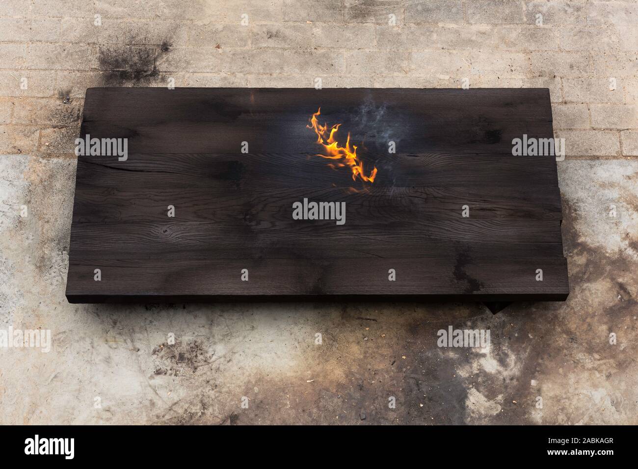 Eine brennende ein großes Stück aus Eichenholz, nur mit einer brennenden Fackel verbrannt, Erstellen von Flammen und Rauch, alte japanische Shou sugi Verbot Technik. schwarze hölzerne Materie Stockfoto