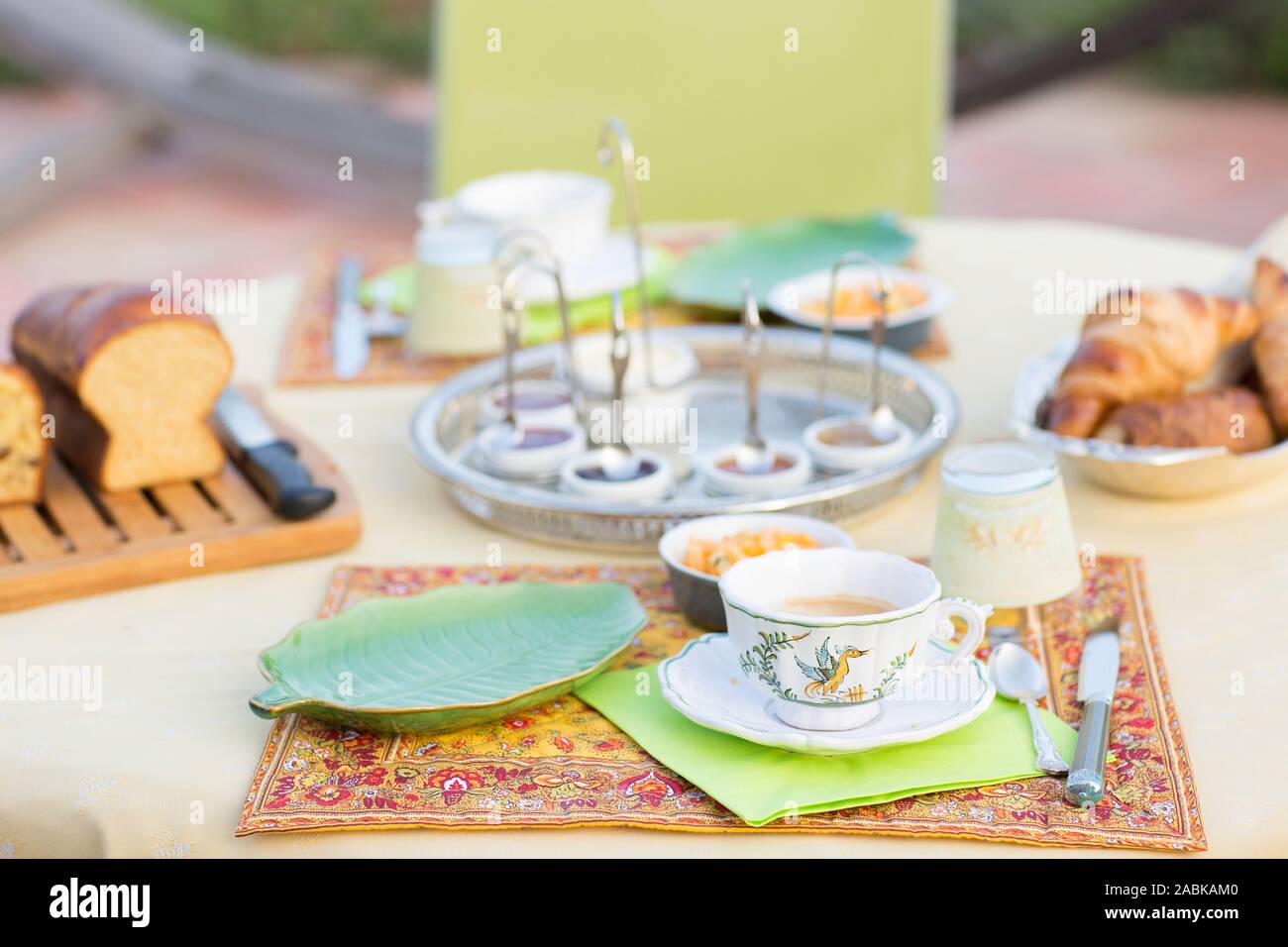 Hausgemachte französische Brioche Frühstück auf einem Schneidebrett mit hausgemachter Marmelade in cups und Croissants. Grün details, Platten und einem klassischen Schale auf dem Tisch o Stockfoto