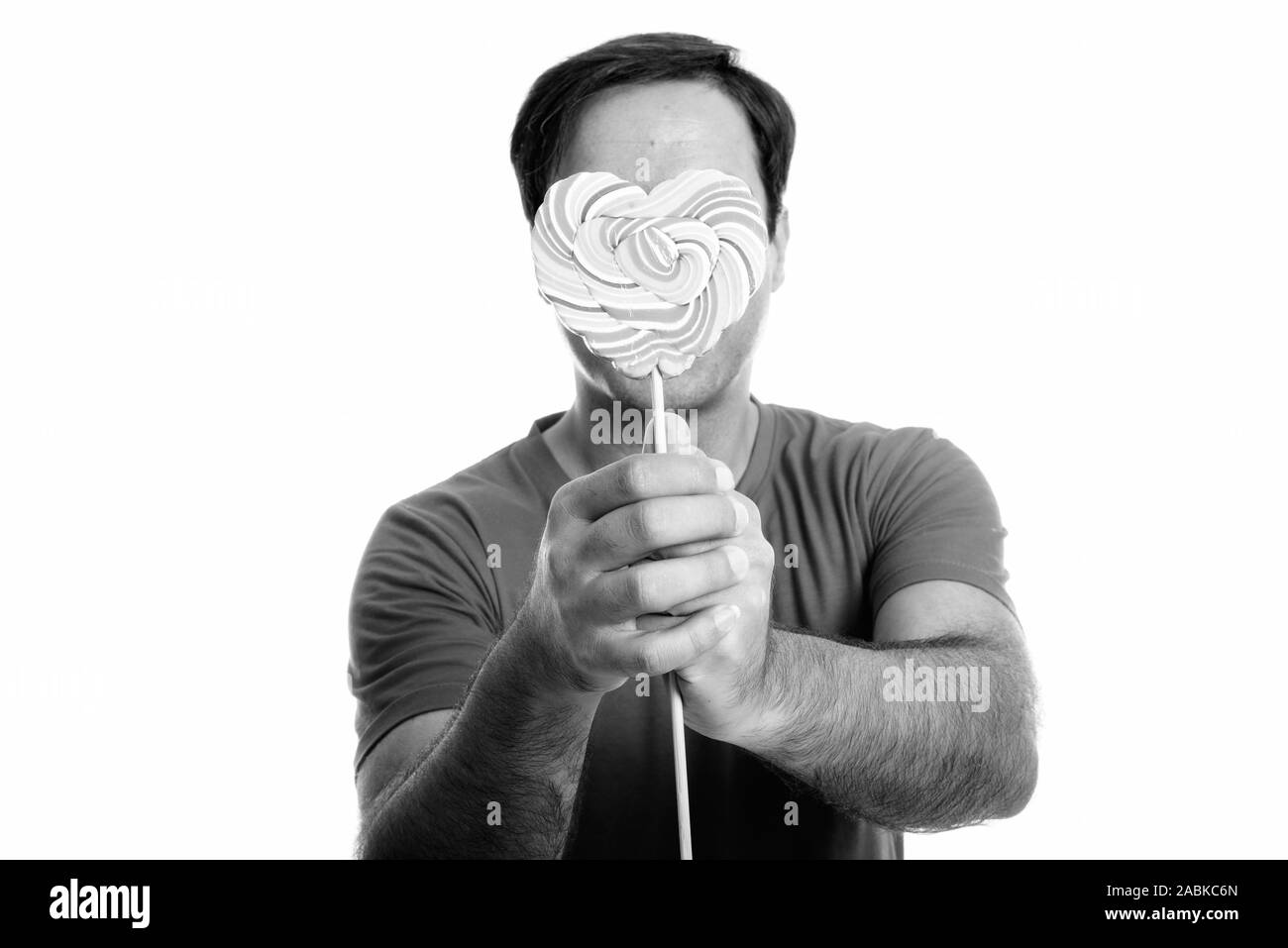 Jungen persischen Mann das Gesicht mit köstlichen Herzförmige bunte Spirale lollipop Stockfoto