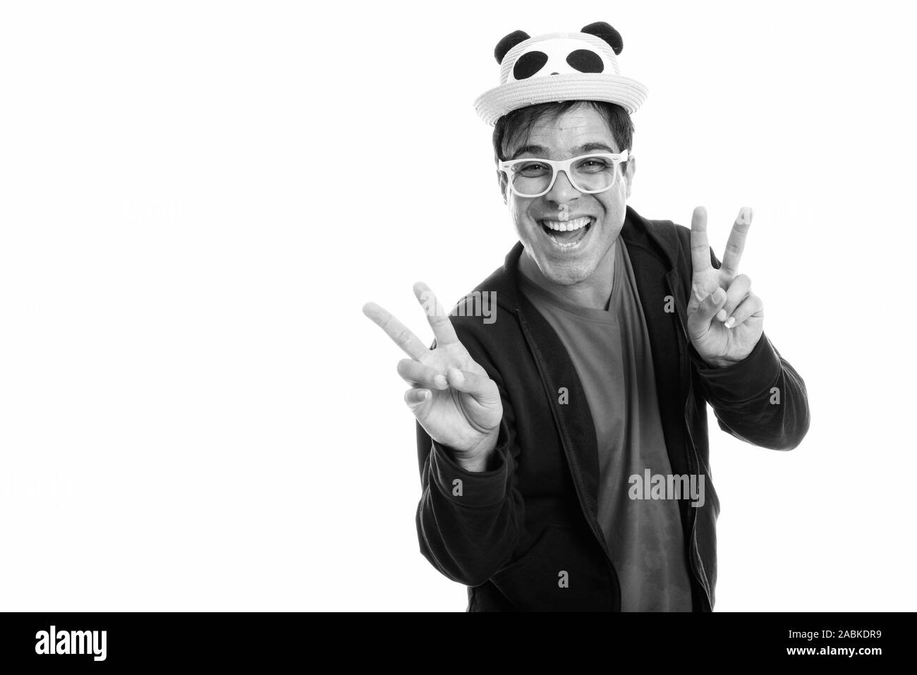 Happy persischen Mann lächelnd und Friedenszeichen mit beiden Händen beim Tragen süße Hut und gelbe Brille Stockfoto