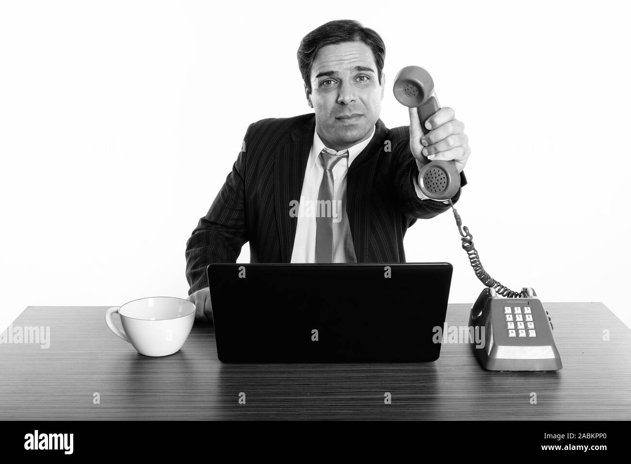 Studio shot der jungen Persischen Geschäftsmann, alte Telefon mit Laptop und Kaffee Tasse auf hölzernen Tisch Stockfoto