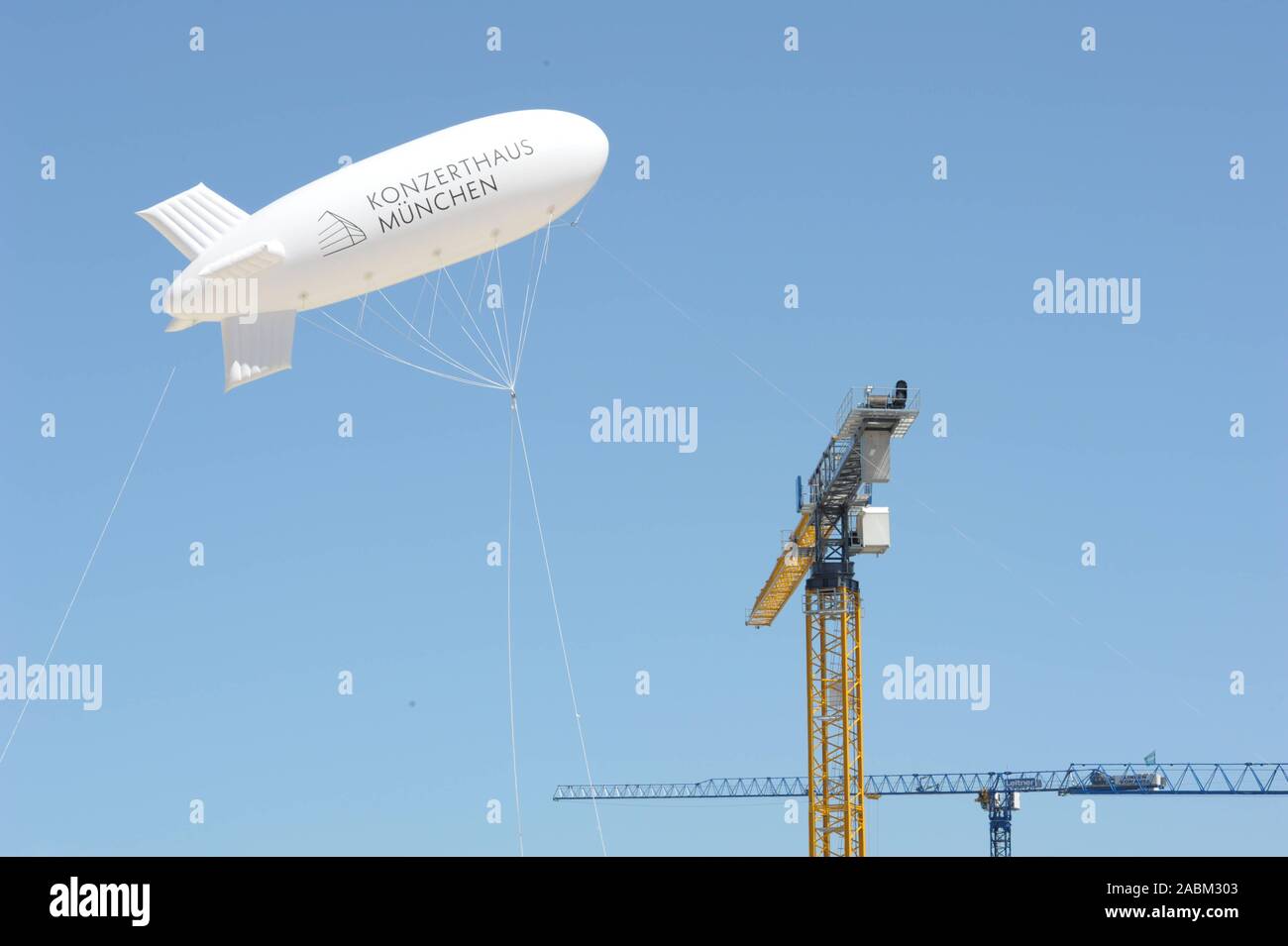 Zeppelin mit Werbung für die neue Konzerthalle oberhalb der Baustelle in der Fabrik Quartal hinter Ostbahnhof. Die neue Konzerthalle ist der Schauplatz des Symphonieorchesters des Bayerischen Rundfunks zu werden. [Automatisierte Übersetzung] Stockfoto