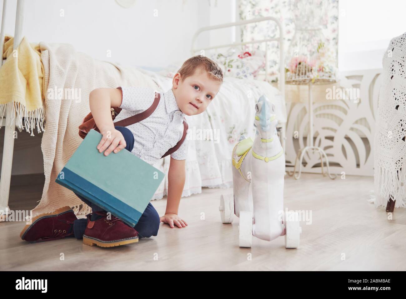 Süße kleine Junge wird zum ersten Mal in die Schule. Kind mit Tasche und Buch. Kid macht einen Aktenkoffer, Kind im Zimmer auf einem Hintergrund Stockfoto