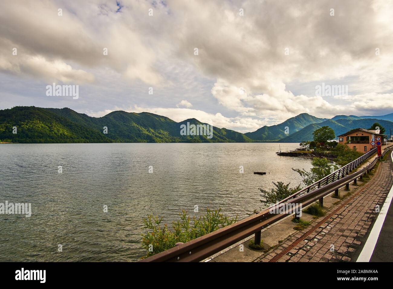 Berge drapiert in Grün und Wolken' shaddows Surround Chuzenji See (Chuzenji-ko) an einem bewölkten Sommertag, in Nikko, Tochigi, Japan Stockfoto
