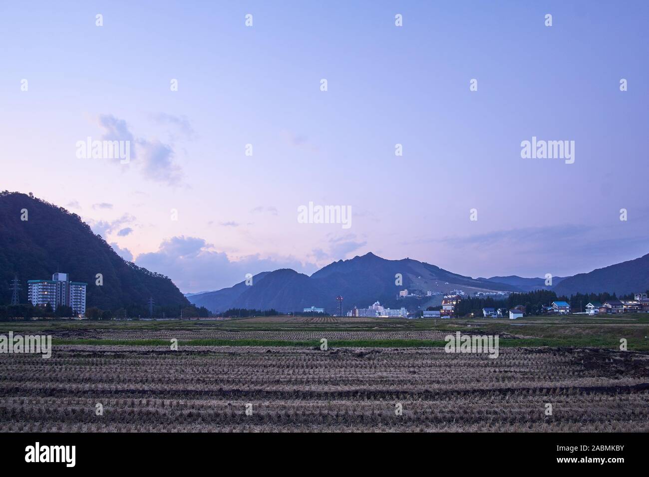 Dämmerung an einem klaren Abend mit lila Berge und abgeerntete Reisfelder auf Tsuchitaru, Yuzawa, Niigata, Japan. Stockfoto