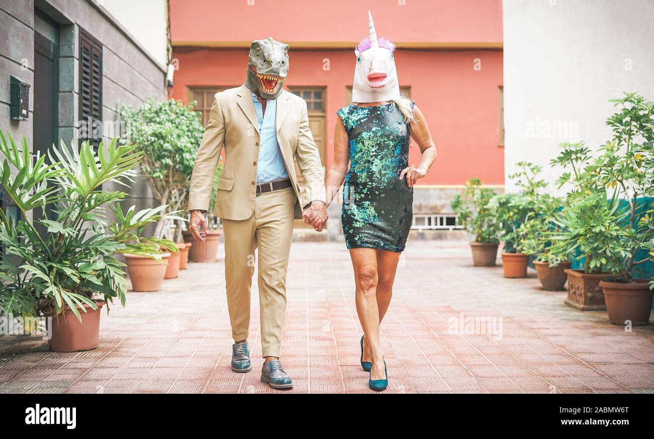 Crazy senior Paar tragen Dinosaurier und Einhorn Maske - Reife trendige Leute Spaß an Karneval Parade maskiert Stockfoto