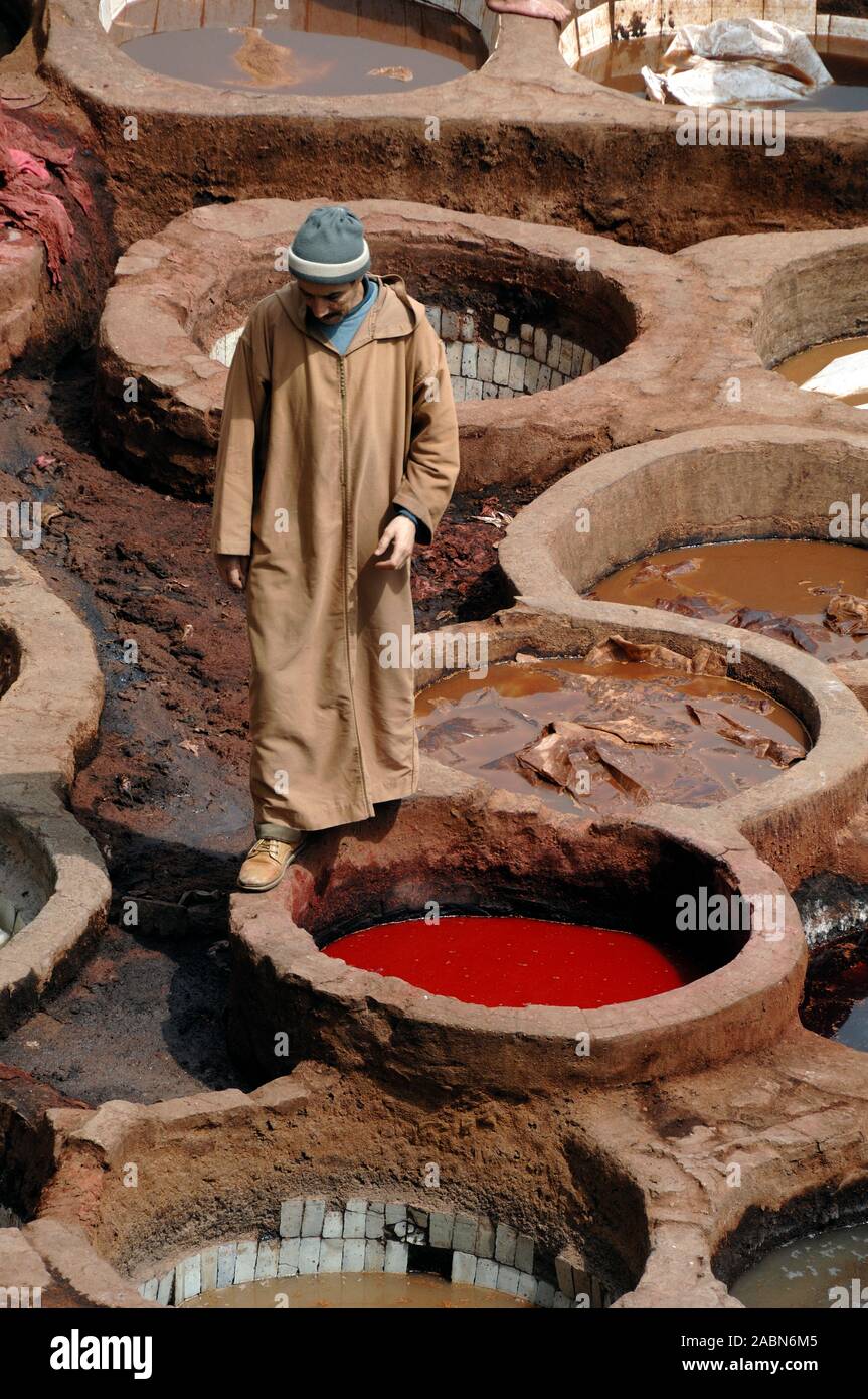 Marokkanische Leder Arbeiter tragen Kaftan & Sterben Gruben incl. Red Poppy Farbstoff an Chouara Gerberei oder Gerbereien in der Fes el Bali Bezirk Fez oder Fes Marokko Stockfoto