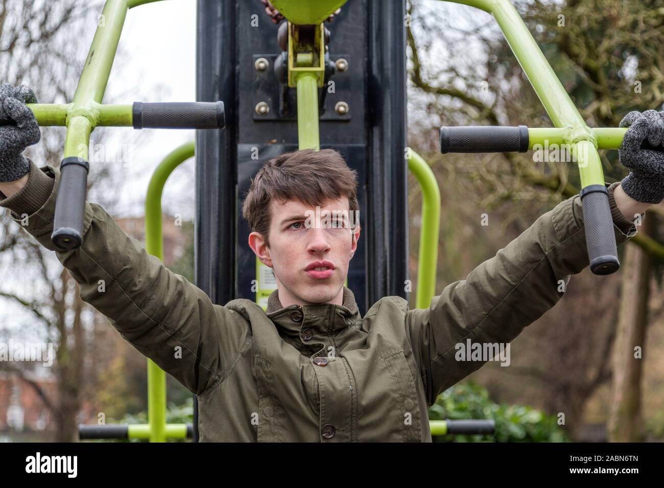 Ein junger Mann im Winter Kleidung arbeiten, die auf Bewegung im Freien Geräte an einem kalten Wintertag. Vielleicht zeigt sein Engagement für die persönliche Entwicklung. Stockfoto