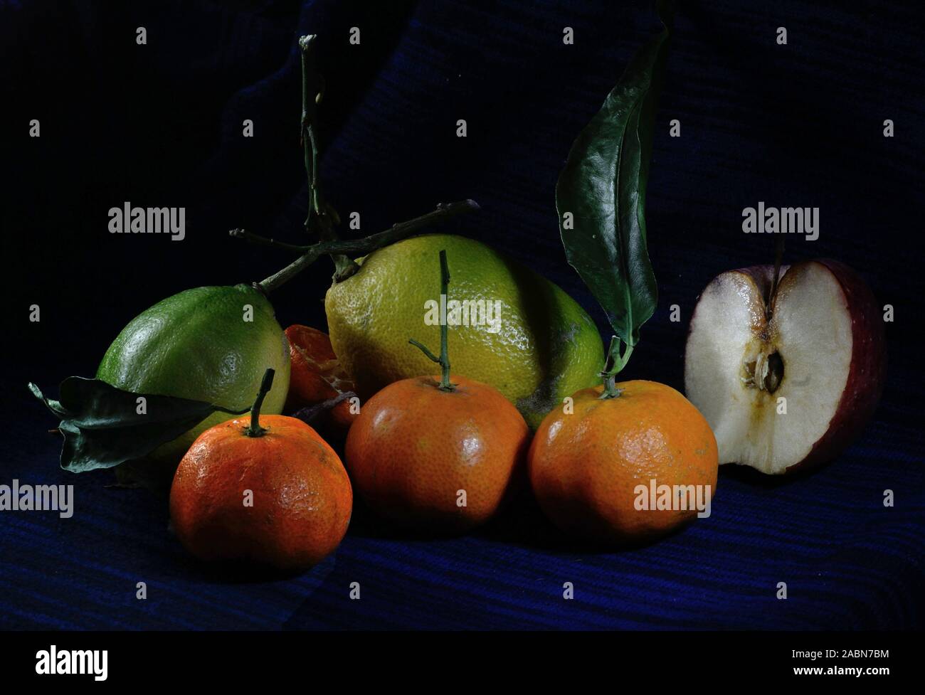 Zitrone und tamiringe Früchte mit einem halben Apfel auf einem dunkelblauen Hintergrund Stockfoto