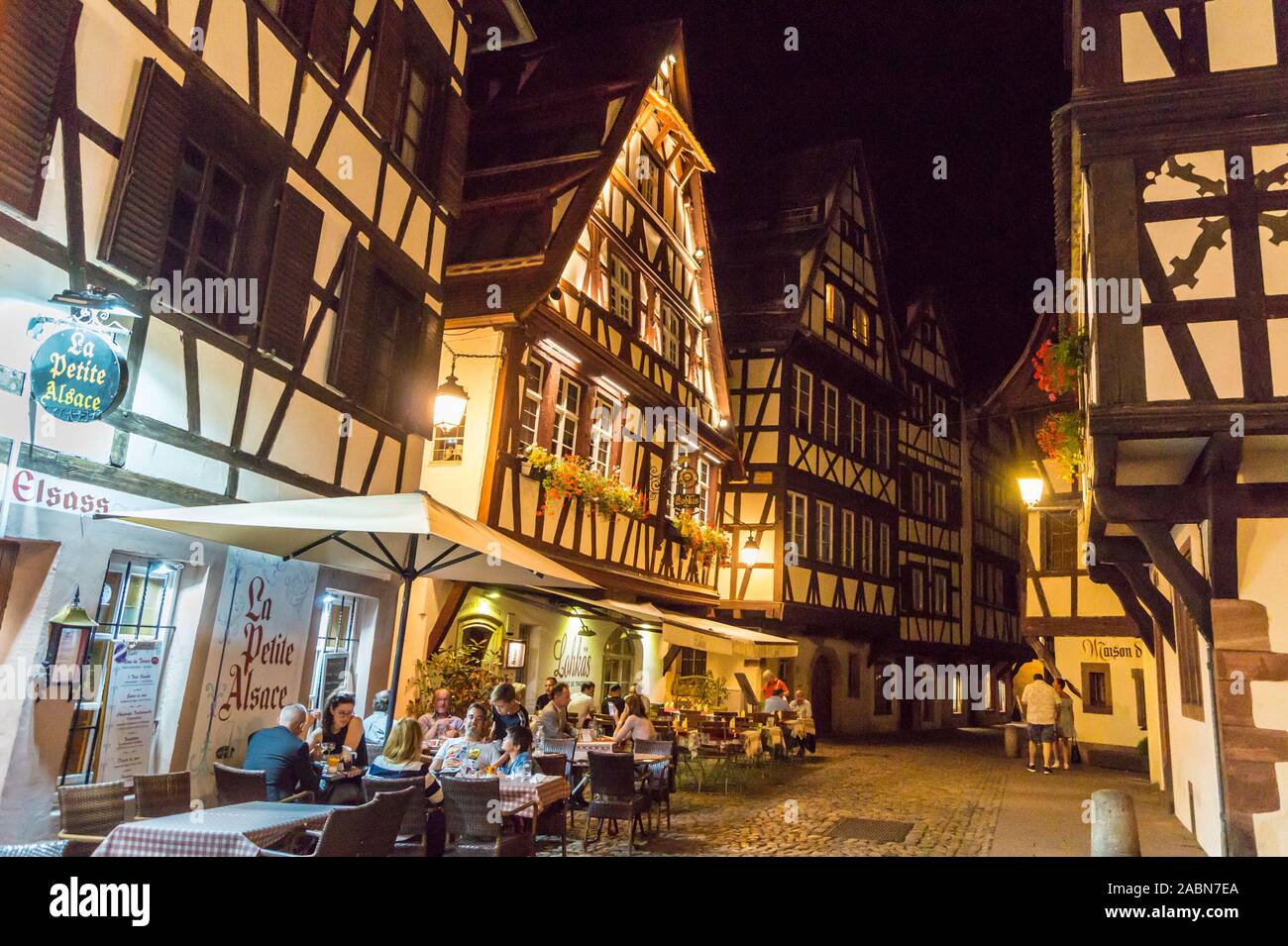 Diners ausserhalb La Petite Elsass Restaurant, und Fachwerkhäuser mittelalterlichen Häusern, in der Dämmerung, Petite France, Straßburg, Elsass, Grand Est, Frankreich Stockfoto