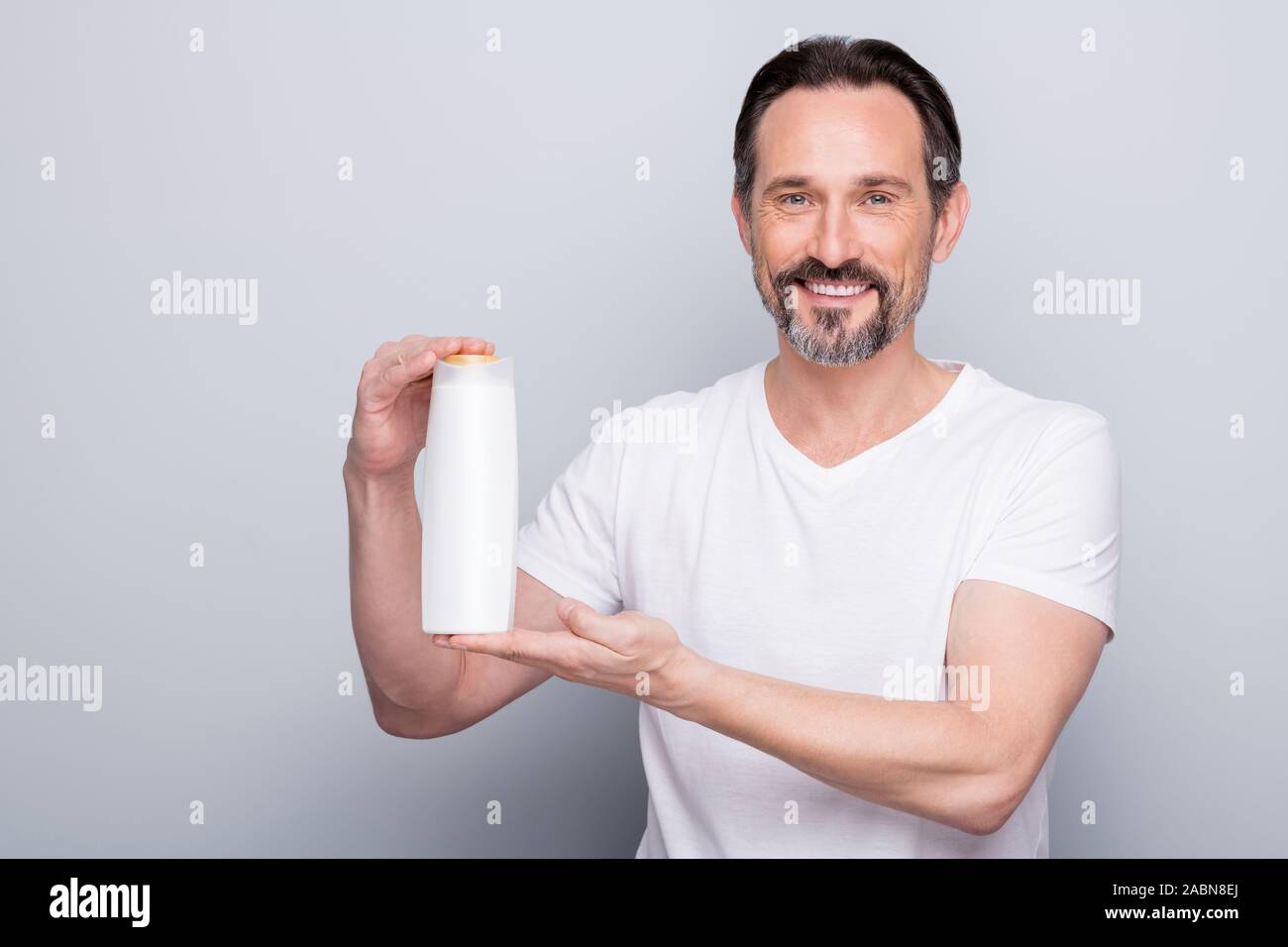 Foto von Stattlichen alter Mann Guy holding Shampoo Conditioner Flasche  zwei in einem erstaunliche Wirkung Werbung Käufer trägt ein weisses T-Shirt  isoliert Farbe grau Stockfotografie - Alamy