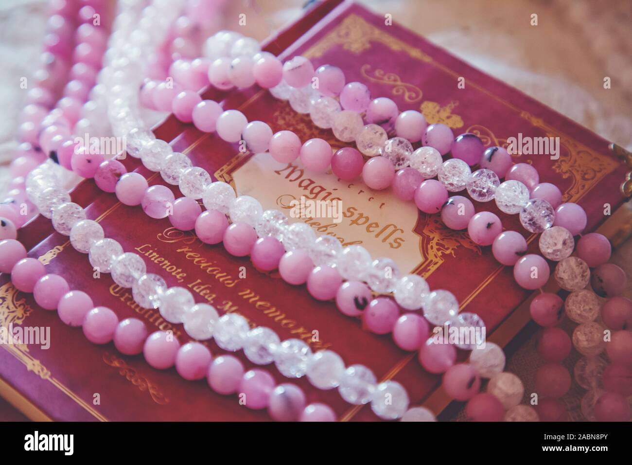 Vintage Buch der Zaubersprüche mit rosa Achat und Quarzkristall Mineral Stein Perlen Stockfoto