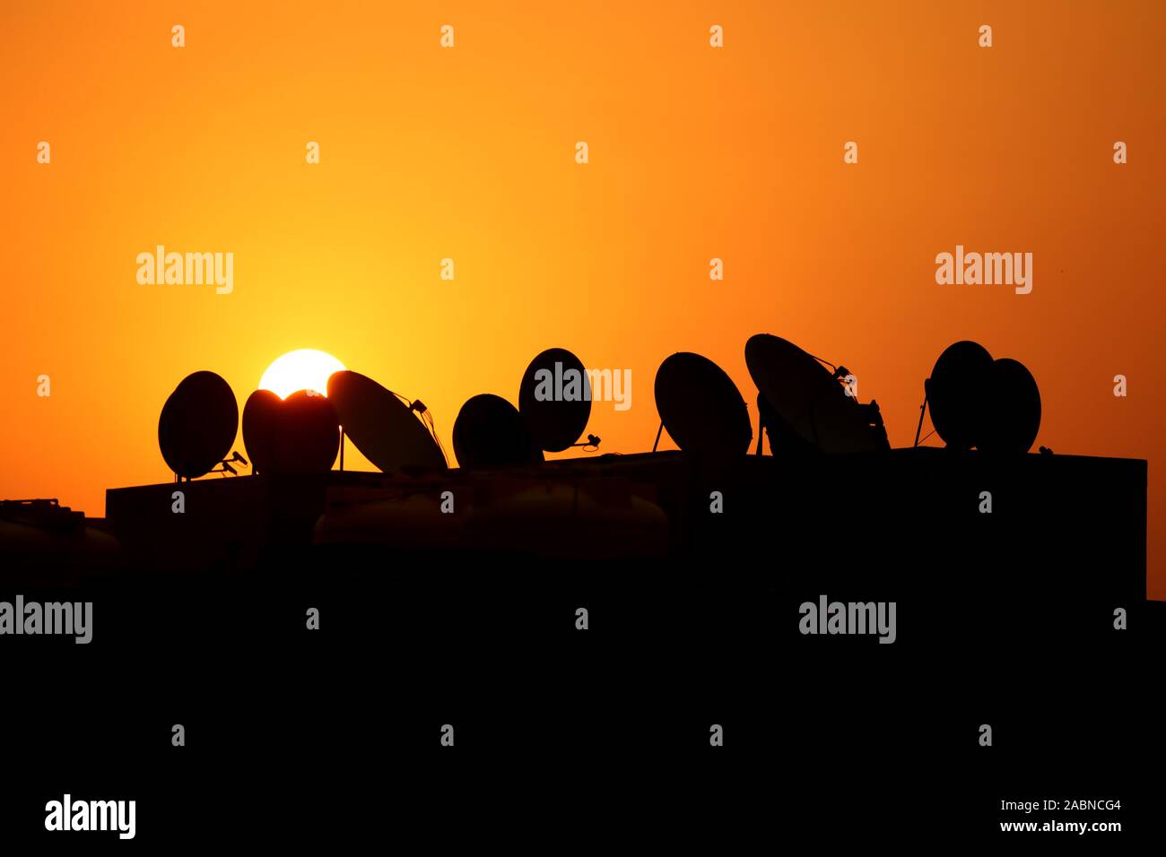 Sat-TV Geschirr silhouetted gegen die untergehende Sonne Stockfoto