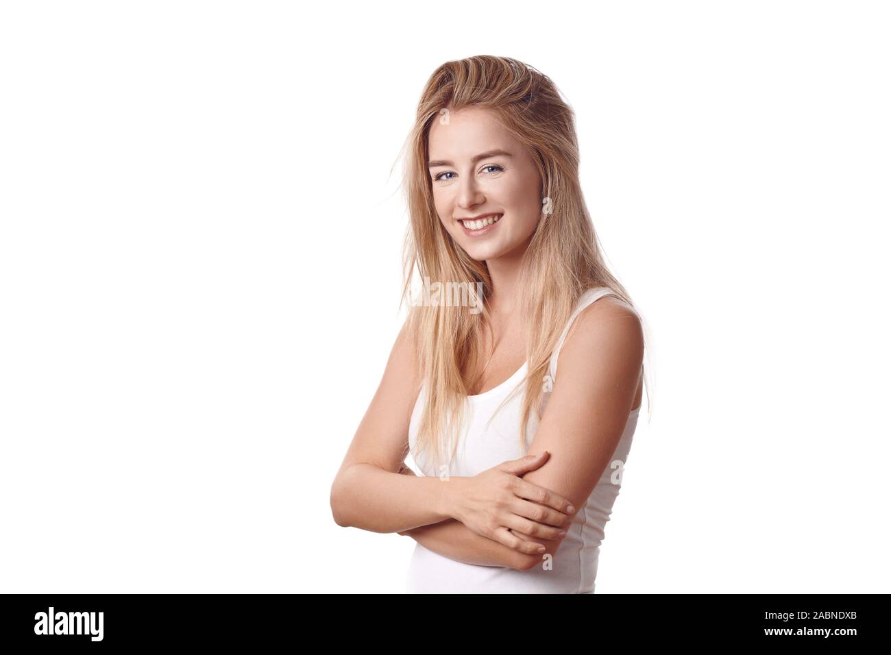 Schöne blonde junge Frau im weißen Hemd mit Waffen gegen weißen Hintergrund gefaltet, lächelnd und mit Blick auf die Kamera. Halbe-halbe Umdrehung - Länge po Stockfoto