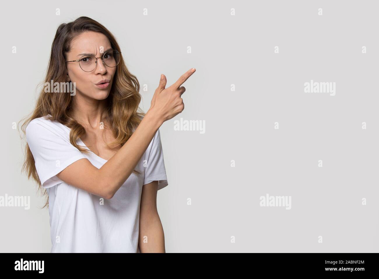 Zweifelnde junge Frau Brille Zeigefinger bei copy Space Stockfoto