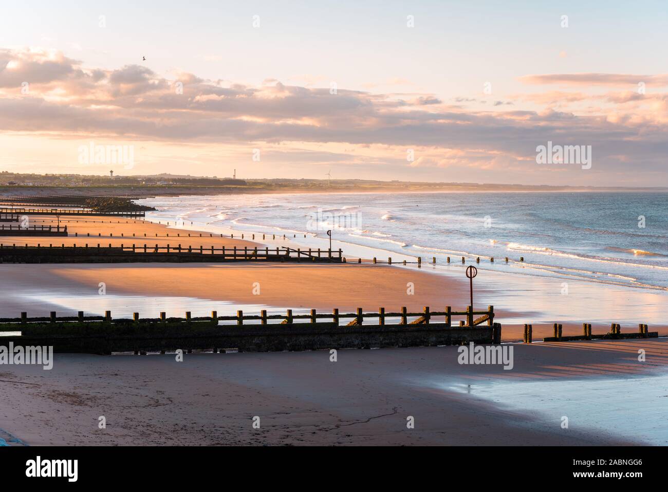 Einsame Sandstrand mit buhnen bei Sonnenuntergang Stockfoto