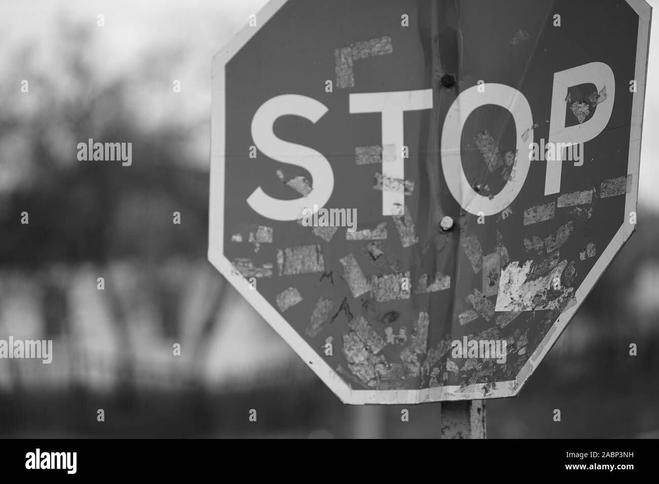 Alt, dreckig verbogen Road Stop Schild close-up, verschwommenes ländliche Haus im Hintergrund. Schwarz-weiß Foto. Stockfoto