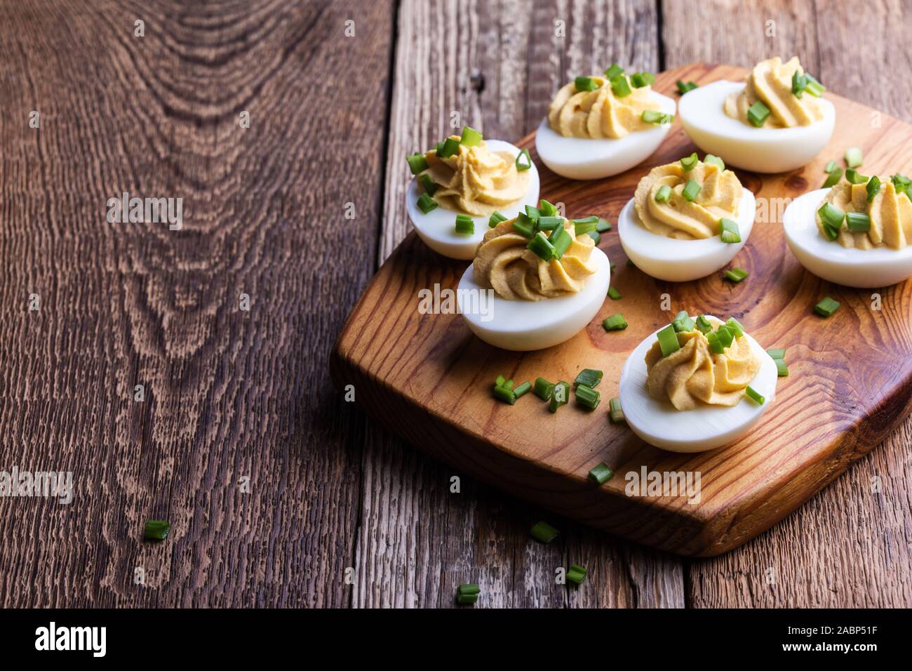 Russische Eier mit grünen Zwiebeln auf rustikalen Holzmöbeln Hintergrund, Ostern party Snack, Nahaufnahme Stockfoto