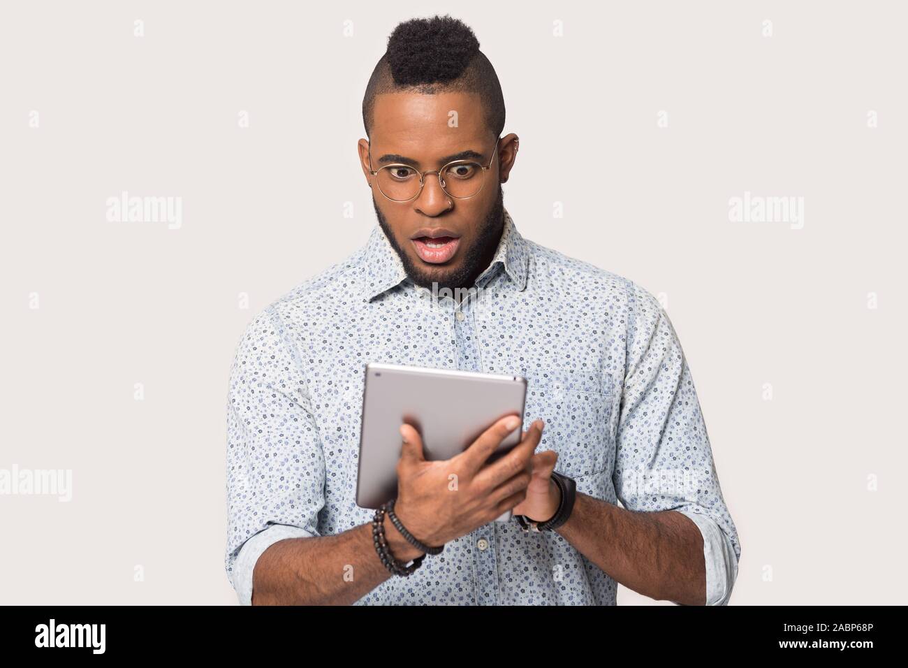 Afrikanische amerikanische Mann an Tablet mit offenen Mund Staunen suchen Stockfoto