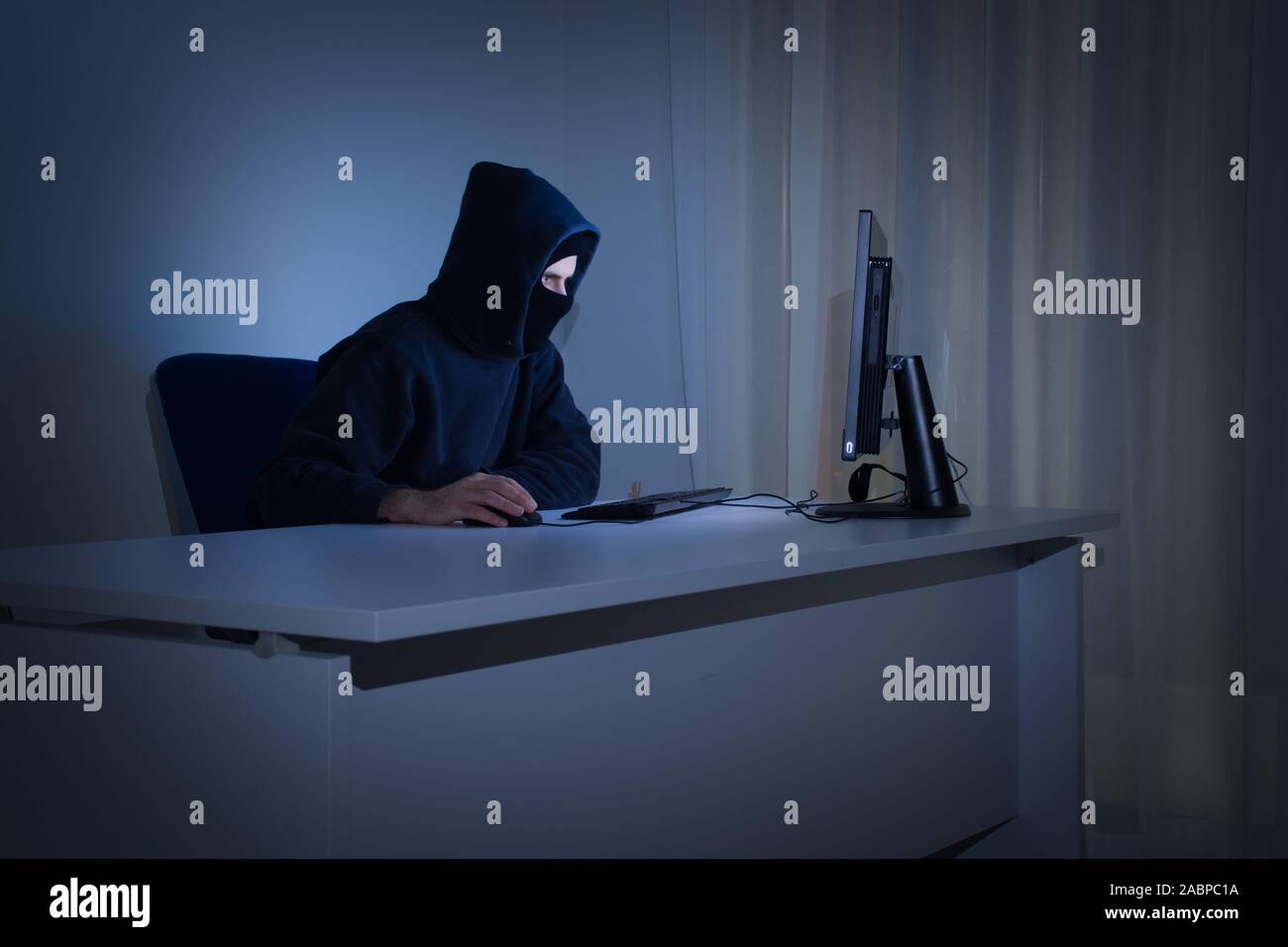 Maskierte Hacker vor, am Computer in dunkle Zimmer stellt die Gefahr für das Surfen im Internet. Internet Security Konzept. Stockfoto