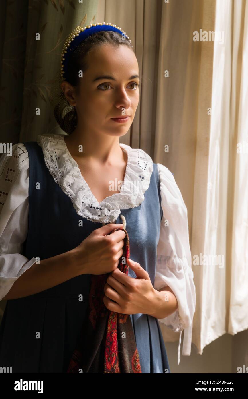 Hübsche junge Frau in der Renaissance kostüm Blick durch das Fenster einer Eigenschaft freigegeben Authentische mittelalterliche Schloss in Frankreich Stockfoto
