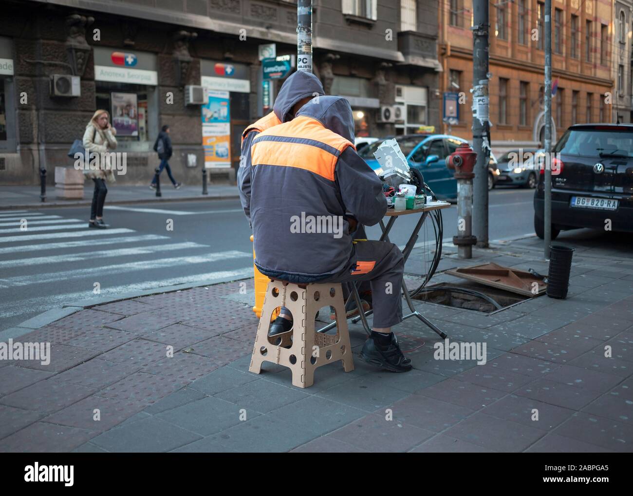 Belgrad, Serbien, 26.November 2019: Zwei Werkstätten Anschluss LWL-Kabel von einem kanaldeckel auf der Straße Stockfoto