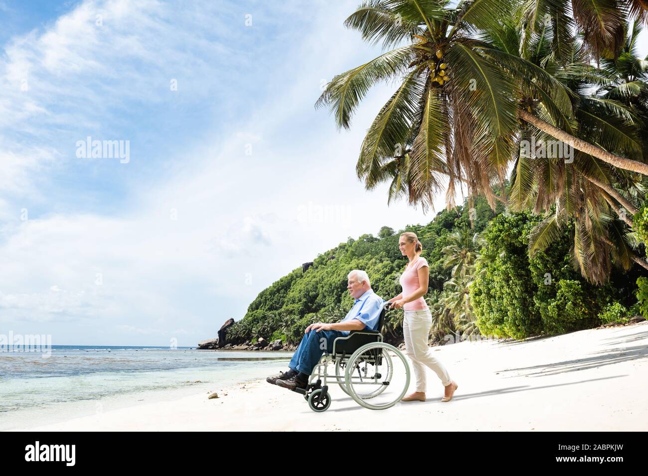 Elder Großvater im Rollstuhl mit Enkelin zu Fuß am Strand. Stockfoto