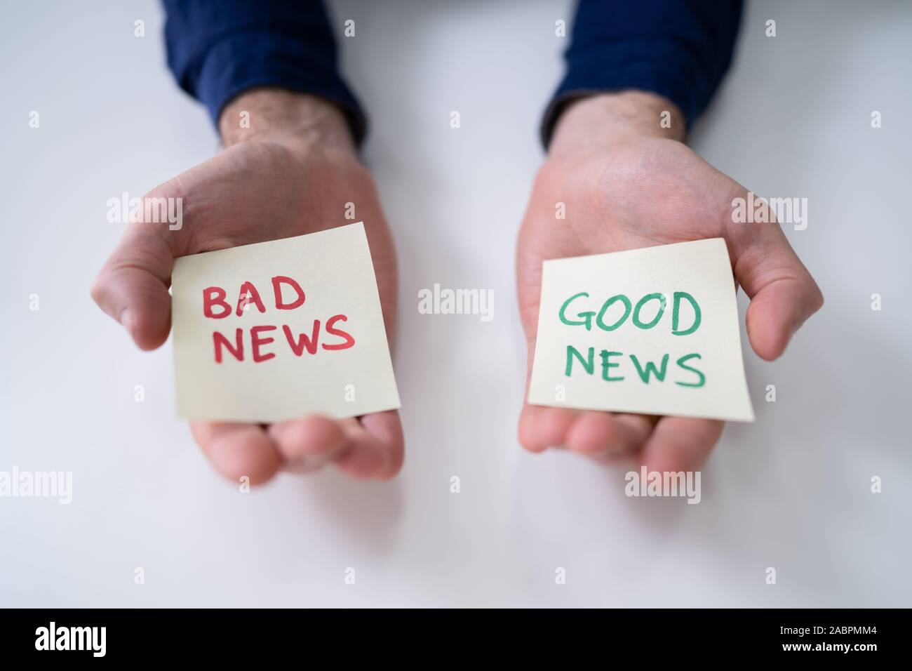 Des Menschen Hand, Papier mit guten und schlechten Nachrichten auf weißem Schreibtisch Stockfoto