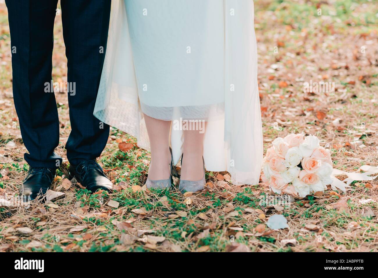 Füße der Bräutigam und die Braut steht auf grünem Gras und Blätter im Herbst mit einem Wedding Bouquet. Stockfoto