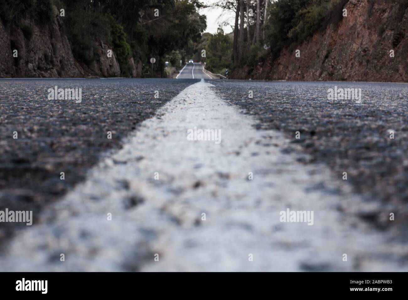 Straße in der Perspektive vom Asphalt mit einem Auto in der Ferne Stockfoto