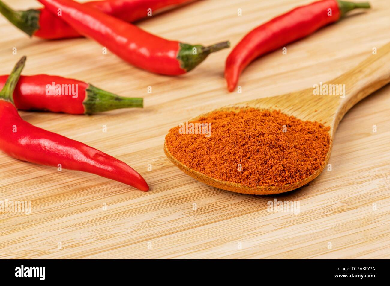 Holzlöffel voller Chili Pulver auf einem hölzernen Hintergrund Stockfoto