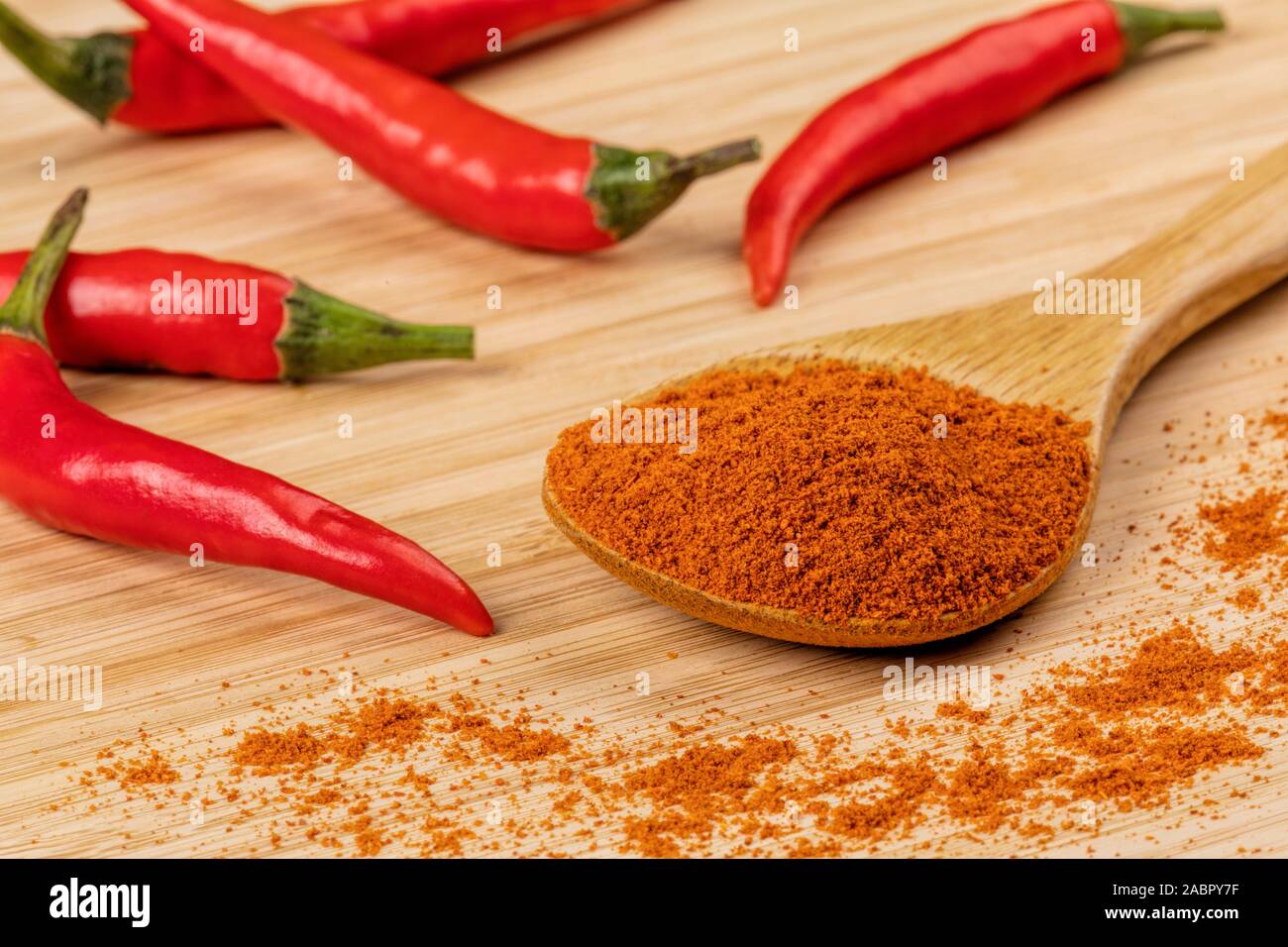 Holzlöffel voller Chili Pulver auf einem hölzernen Hintergrund Stockfoto