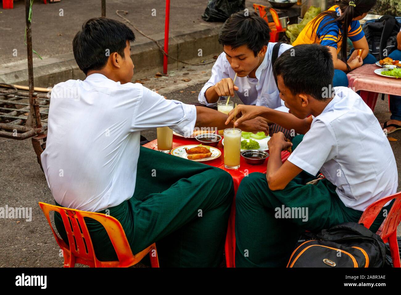Eine Gruppe junger Leute Essen an einer Garküche, Yangon, Myanmar. Stockfoto