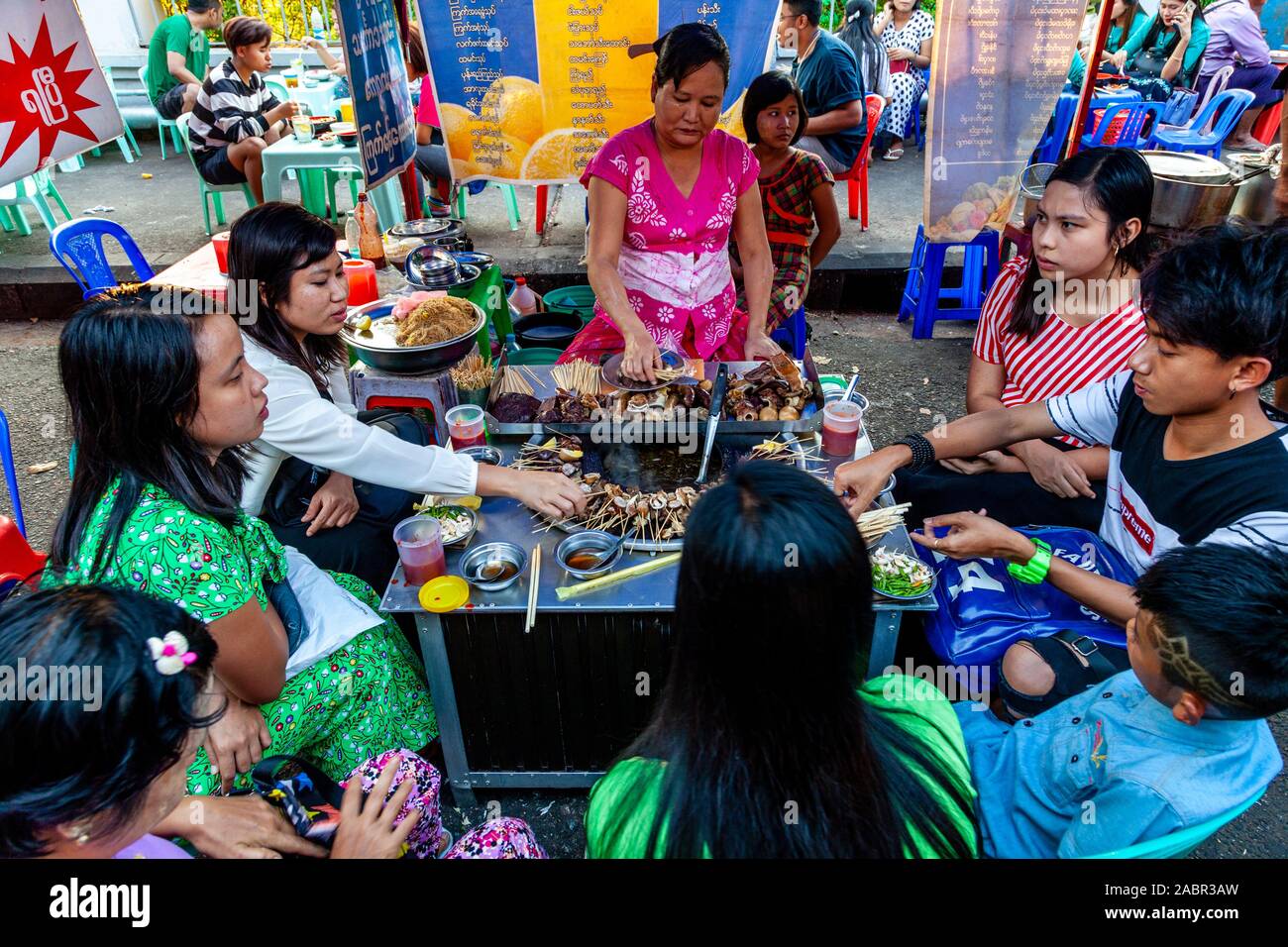 Eine Gruppe junger Menschen essen Essen aus einem Stall in der Innenstadt von Rangun, Yangon, Myanmar. Stockfoto