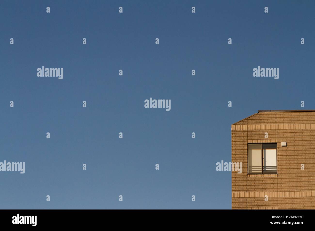 Abstraktes Bild eines Fensters oben in einem Ziegelgebäude unten rechts im Rahmen, mit blauem Himmel. Tokio, Japan Stockfoto