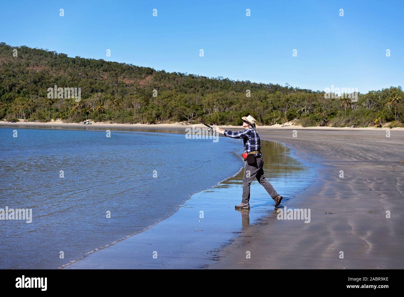 Rentner casting seinen Stab beim Angeln am Strand Stockfoto