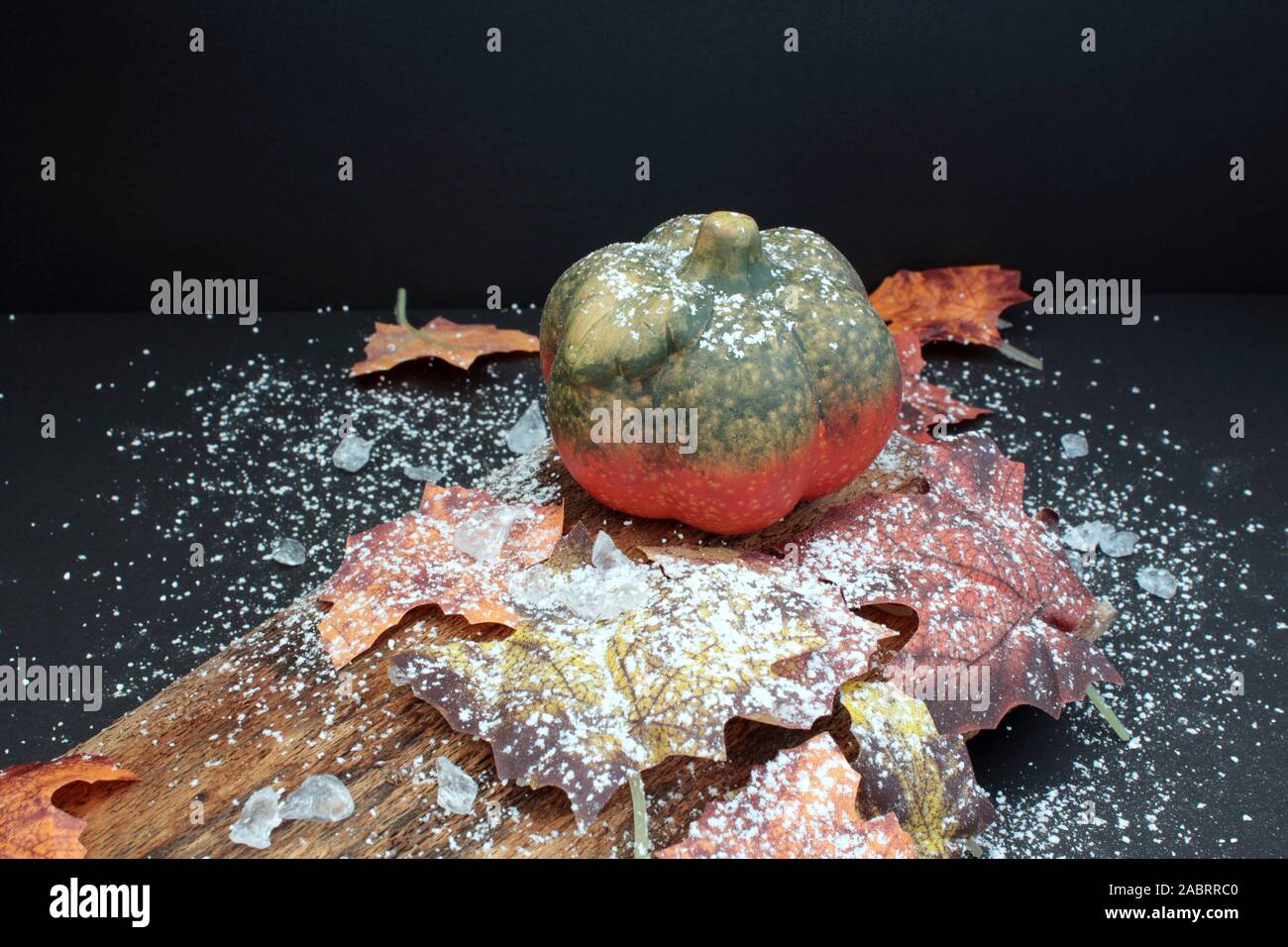 Autumnally dekoriert Kürbis mit Herbstlaub, Schnee- und Eiskristalle Stockfoto