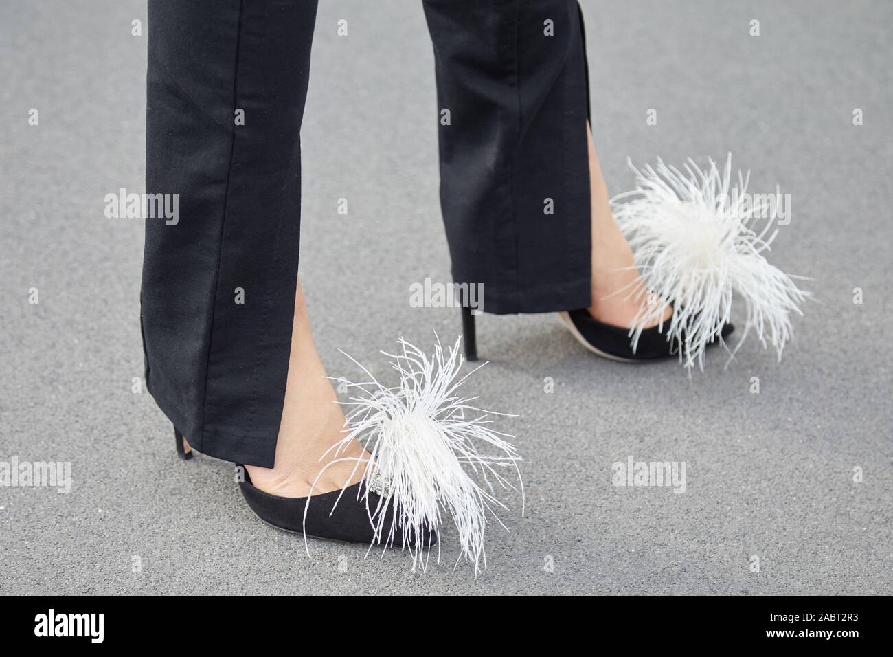 Mailand, Italien - 18 SEPTEMBER 2019: Frau mit schwarzen High Heel Schuhe mit weissen Federn vor Prada fashion show, Mailand Fashion Week street style Stockfoto