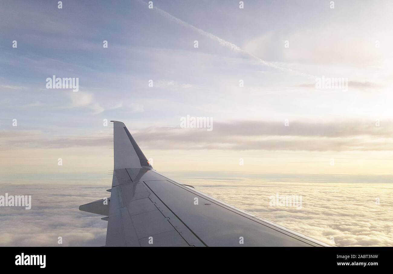 Fliegen weg auf Urlaub, die Tragflächen eines Flugzeugs fliegen hoch in den Wolken Stockfoto