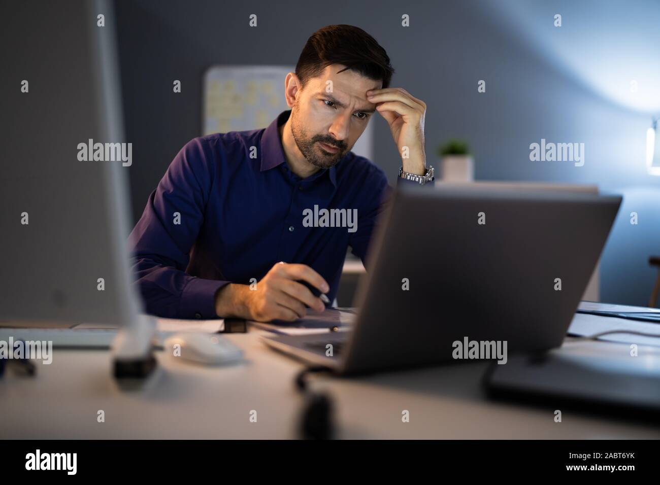 Betonte Buchhalter sitzt mit dem Kopf in der Hand während der Arbeit spät im Büro Stockfoto