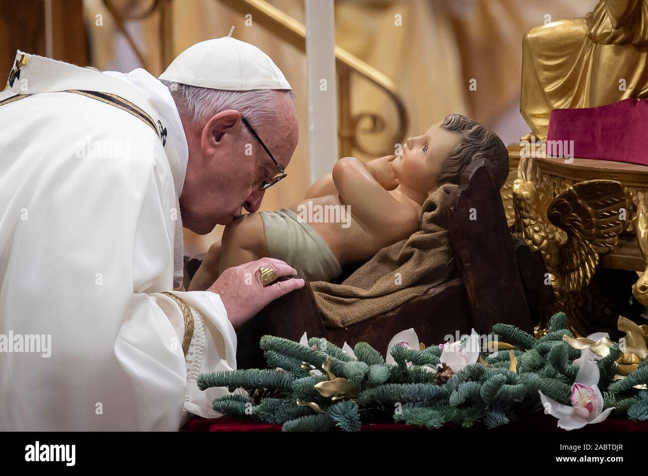 Papst Franziskus küsst ein Baby Jesus Abbildung (Statue) als er ankommt Erscheinung der Heiligen Messe im Petersdom, Vatikan Stadt zu feiern. Stockfoto