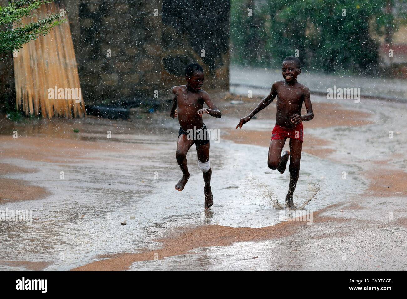 Regenzeit in einem afrikanischen Dorf. Jungen laufen unter der regen Togo. Stockfoto
