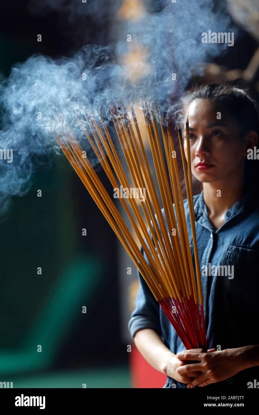 Ha Chuong Hoi Quan Pagode. Junge chinesische betende Frau mit großen Räucherstäbchen in der Hand. Ho Chi Minh City. Vietnam. Stockfoto
