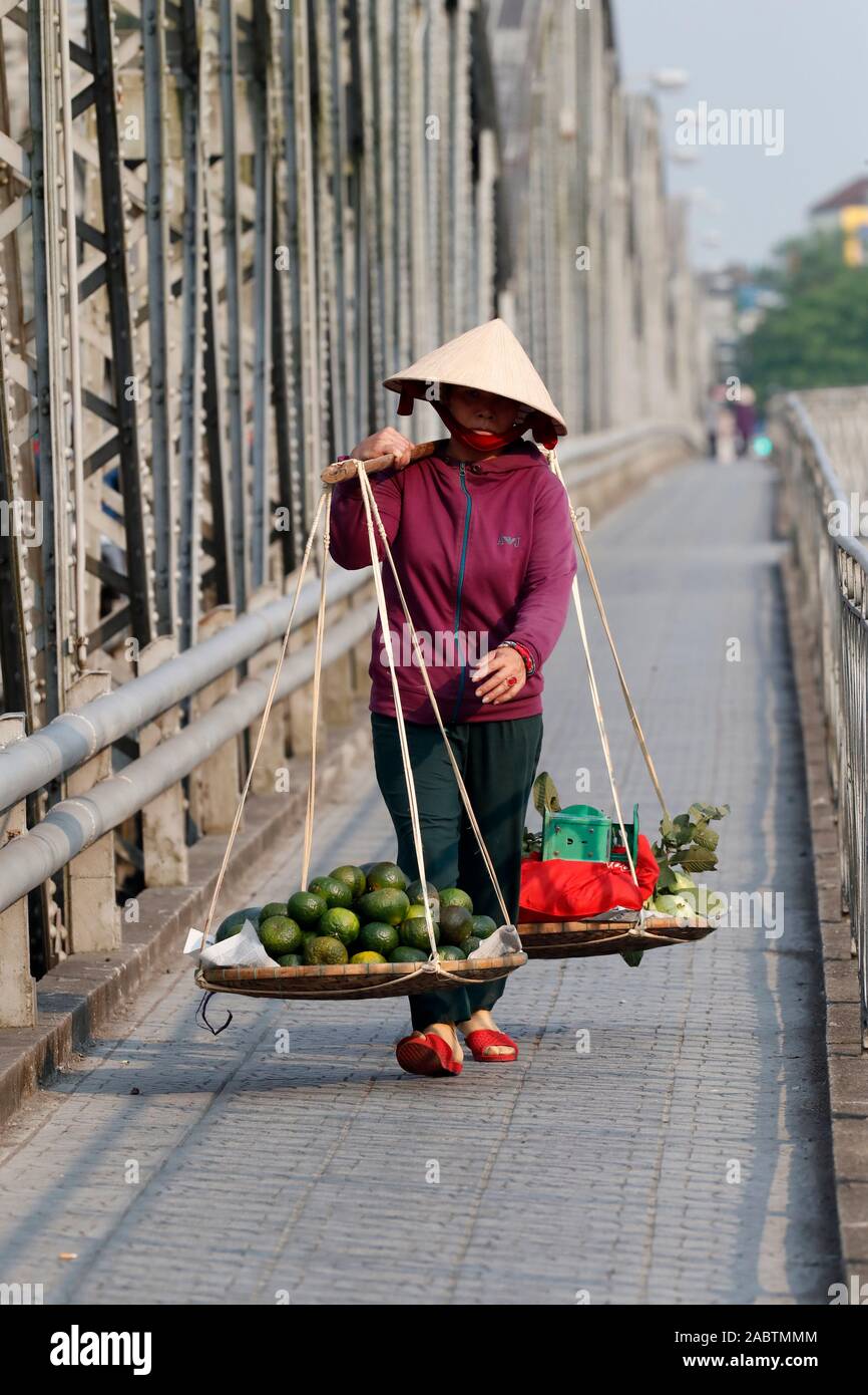 Vietnamesische Frau, die Körbe mit Früchten auf dem berühmten Trang Tien Brücke. Farbton. Vietnam. Stockfoto