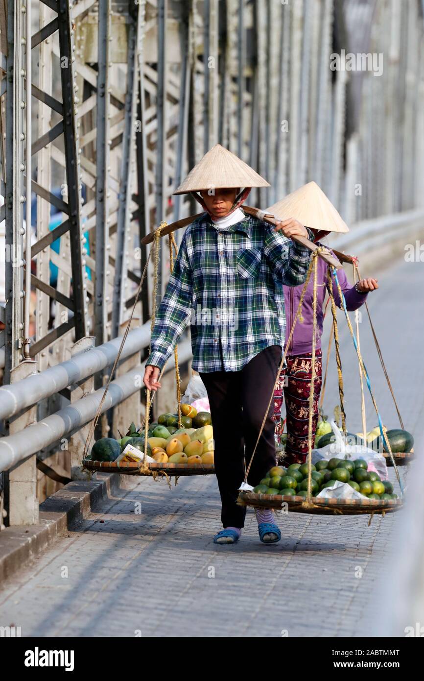 Vietnamesische Frauen die Körbe mit Früchten auf dem berühmten Trang Tien Brücke. Farbton. Vietnam. Stockfoto